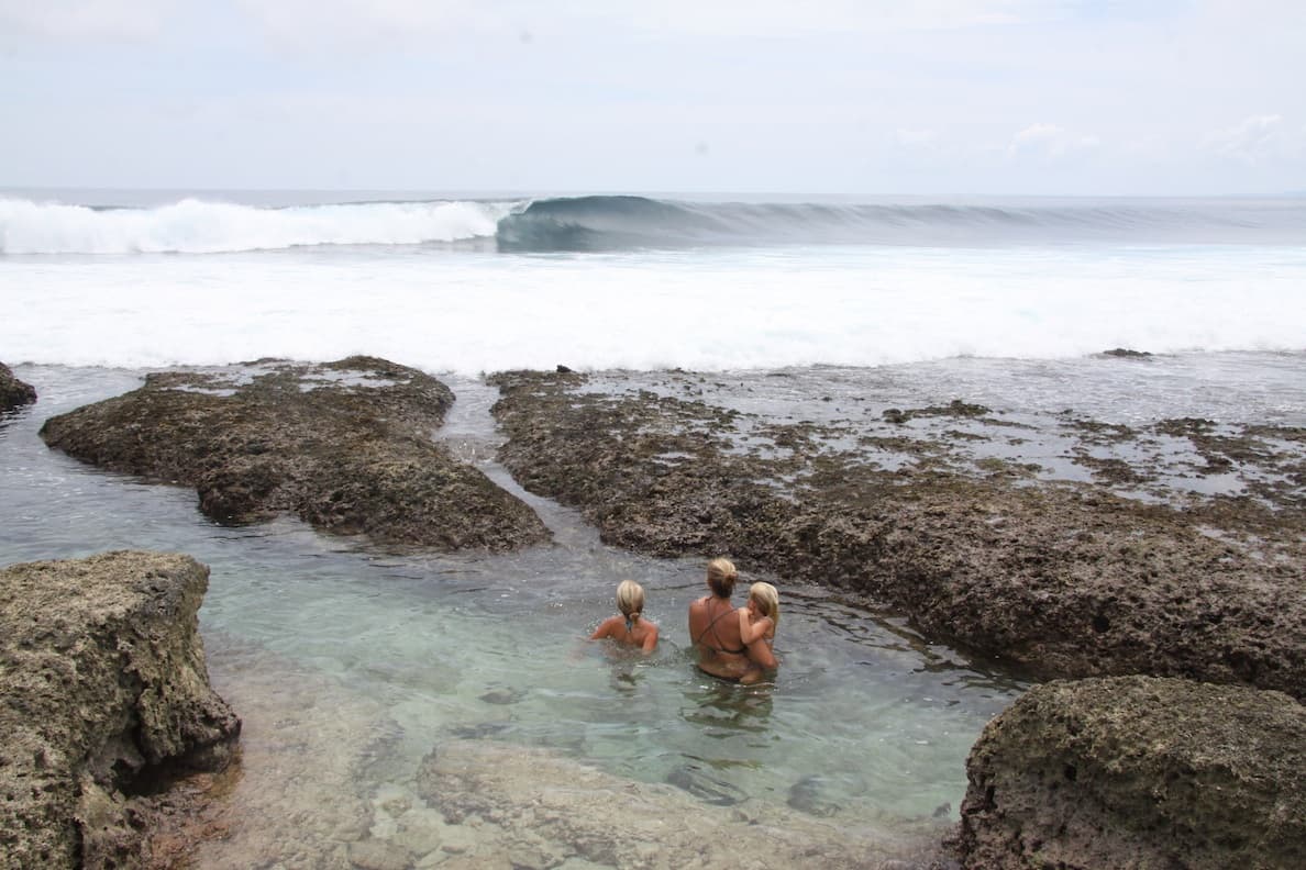 People relaxing in a clear tide pool at Asu Island