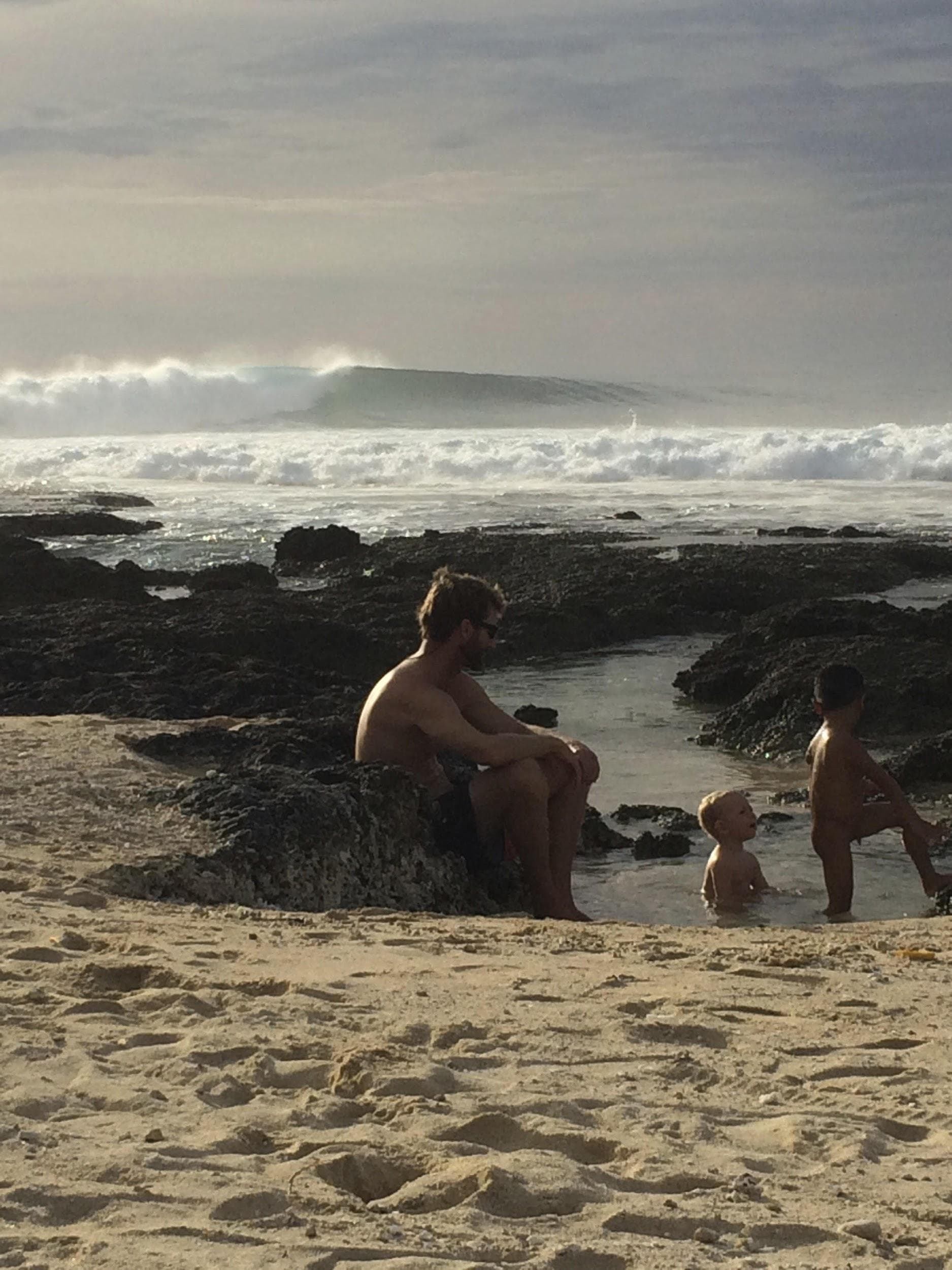 Family sitting near tide pools on the beach at Asu Island