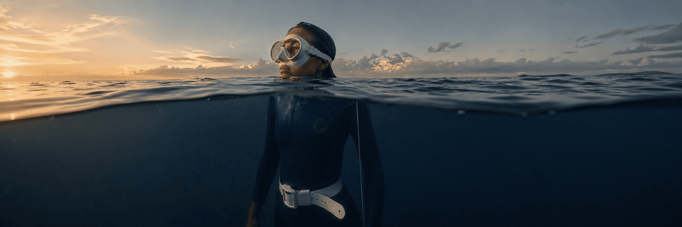 A freediver at the ocean surface at sunset