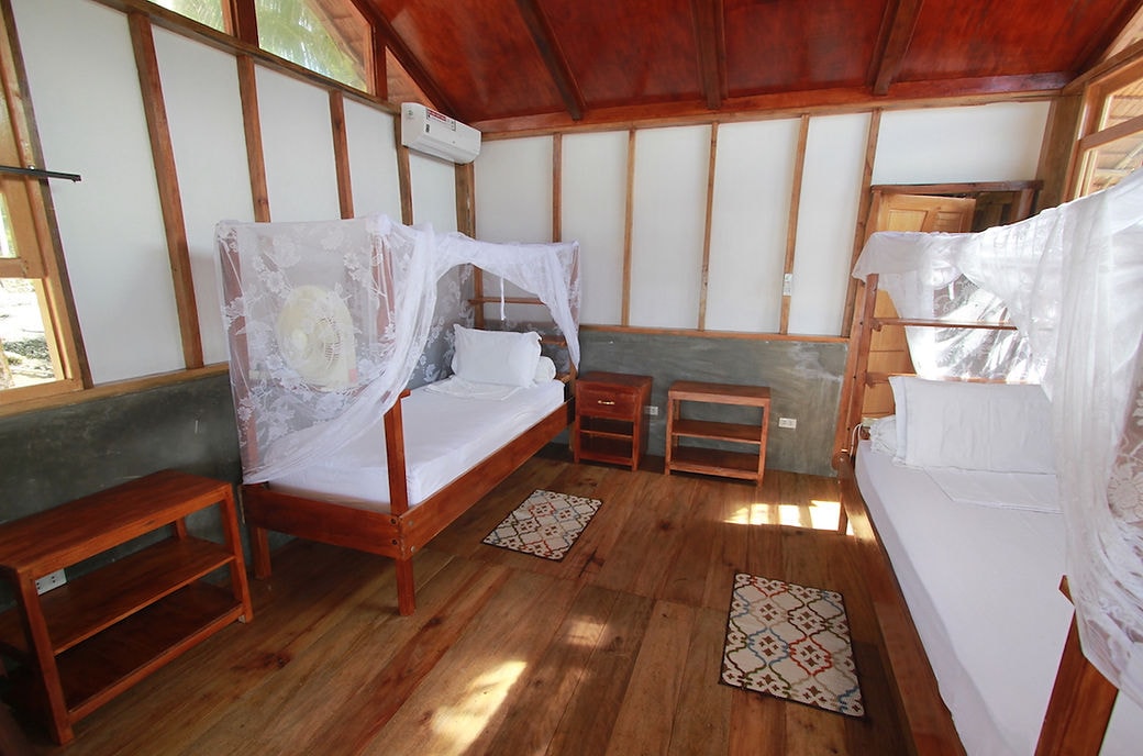 Bungalow interior at Asu Camp with two beds under mosquito nets