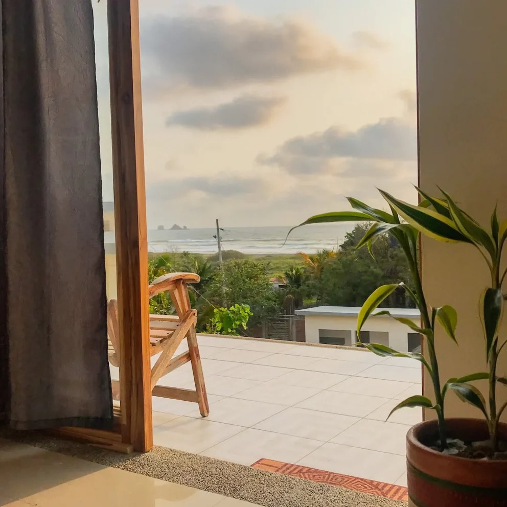 An open balcony door looking down to the coast at dusk