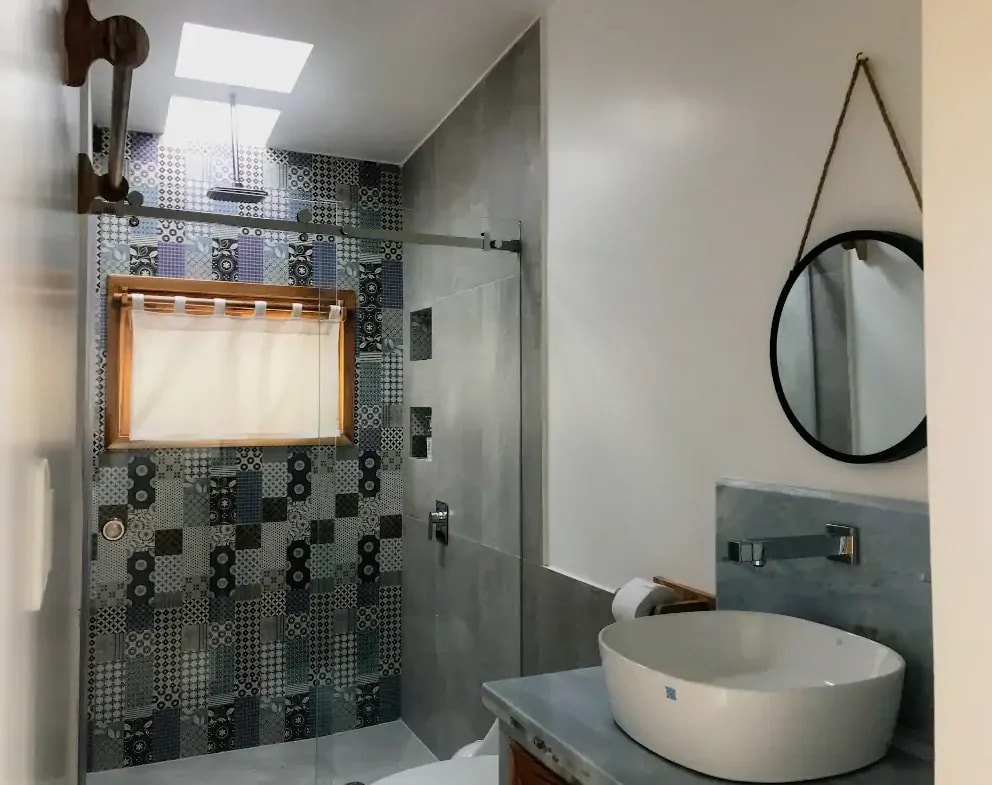 A tiled walk in shower and a round mirror over the basin
