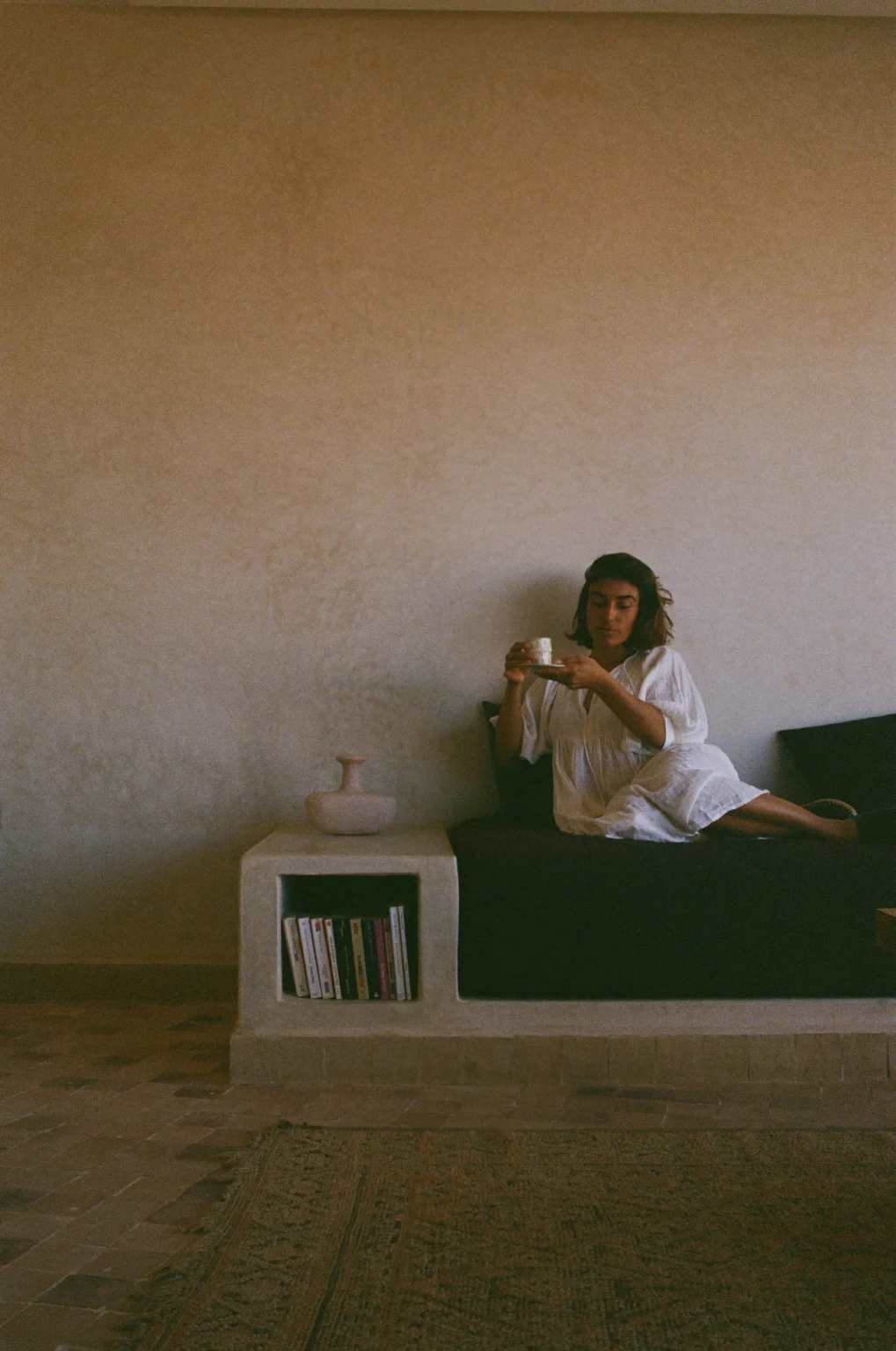 A guest sitting with coffee on the built-in bench in the lodge lounge