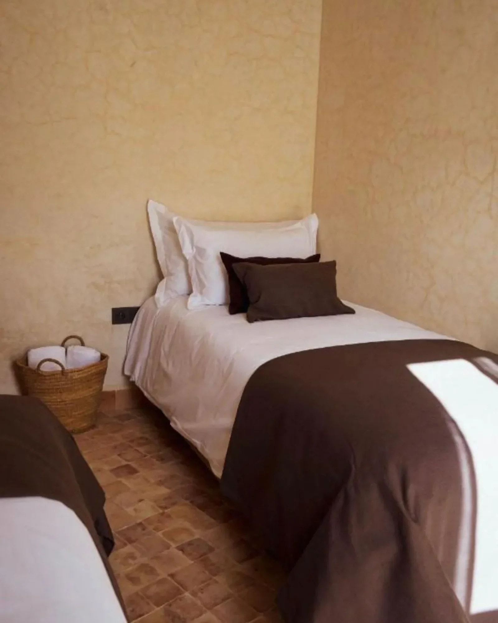 A bed under plastered walls in one of the lodge rooms