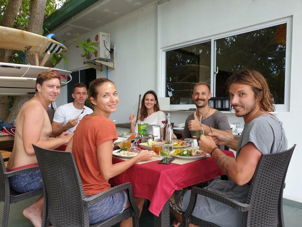 Guests eating lunch on the porch with surfboards racked behind them