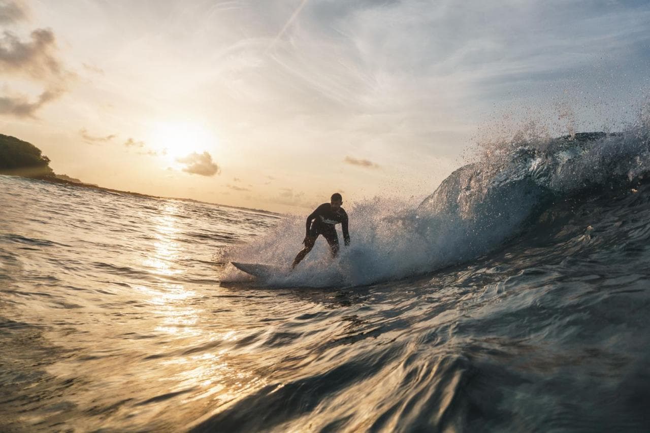 Surfer dropping into a sunset barrel near Himmafushi, North Male Atoll