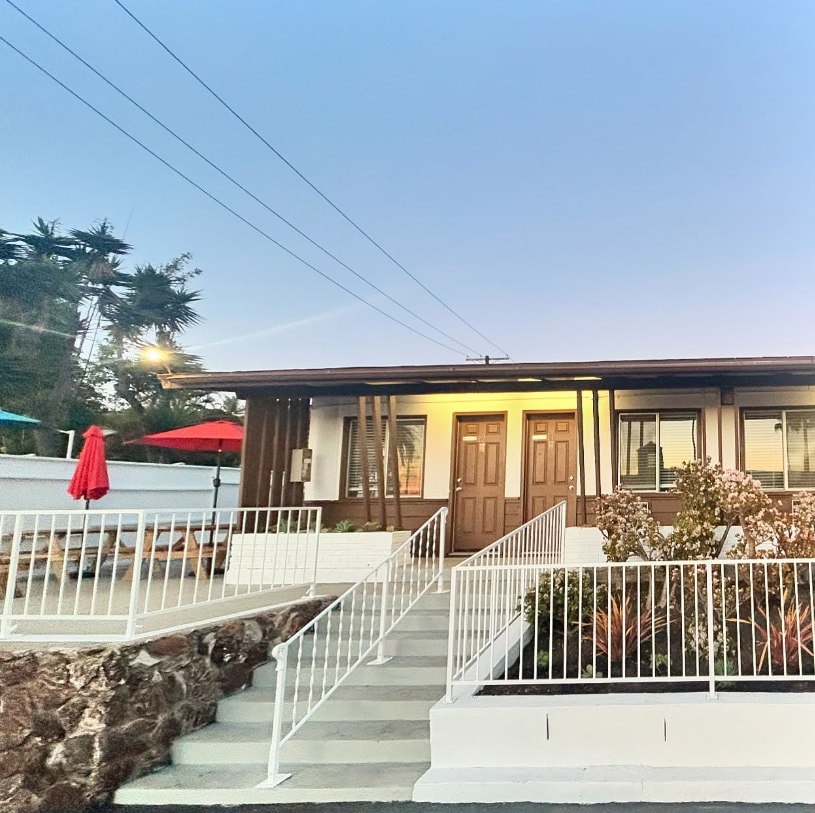 The hotel at dusk, lit doorways and a red umbrella over the picnic tables