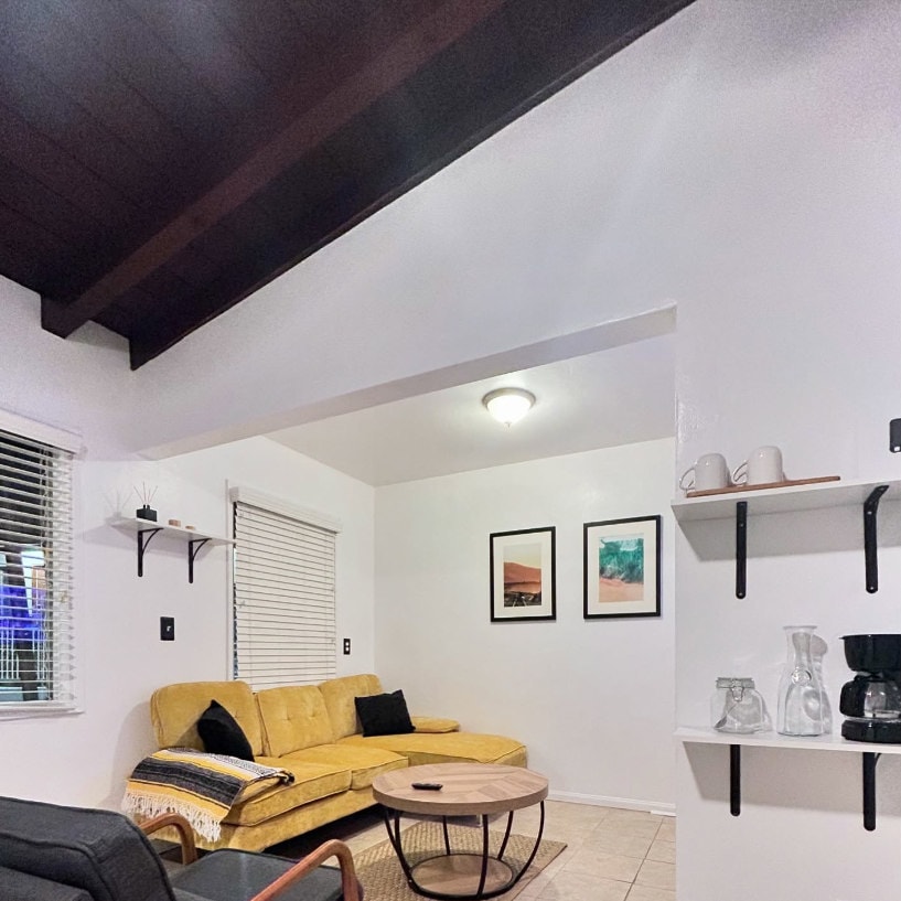 The shared living room with a yellow sofa, coffee maker and open shelves