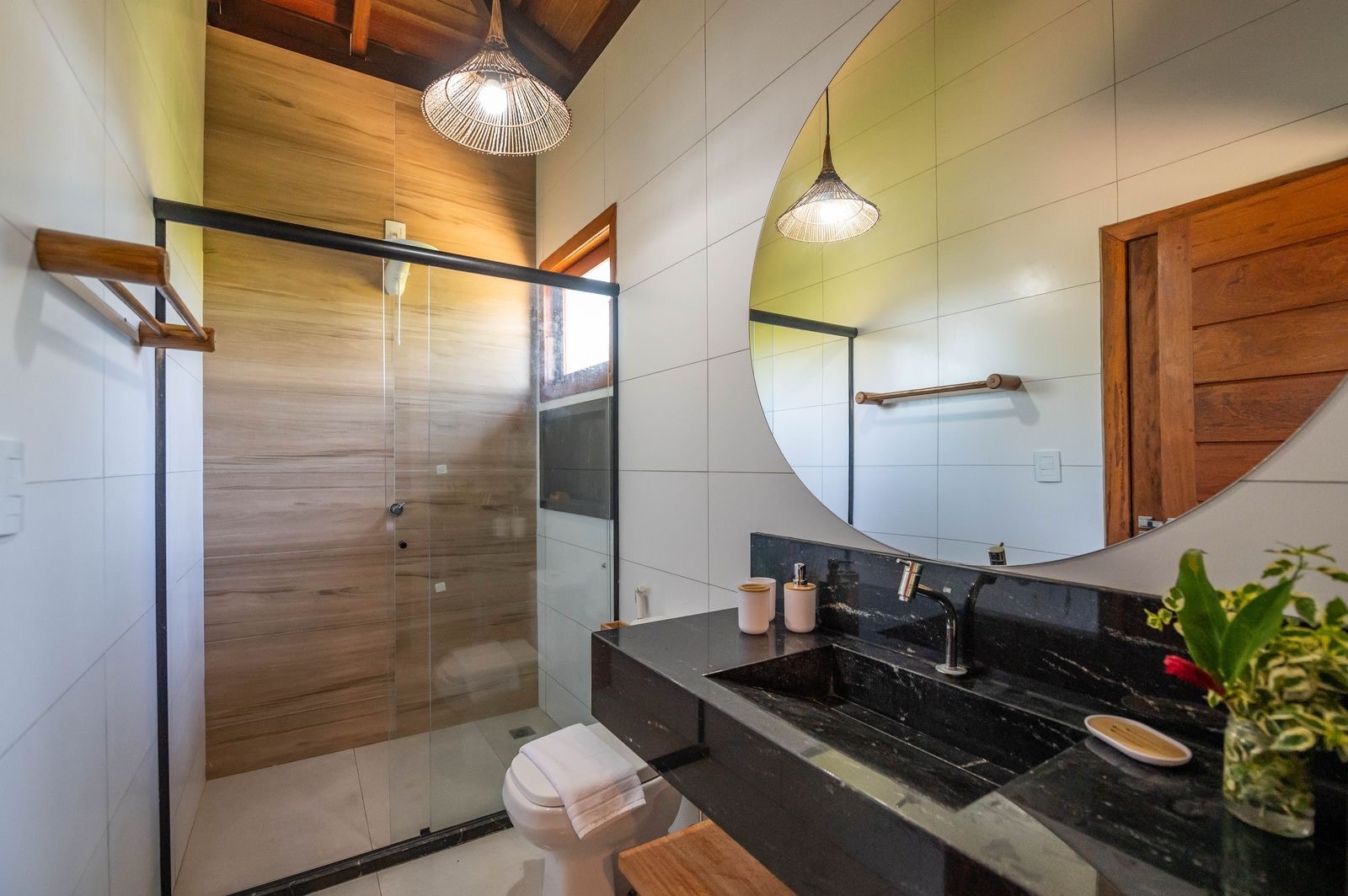 Bathroom with a walk-in shower, round mirror and a stone vanity