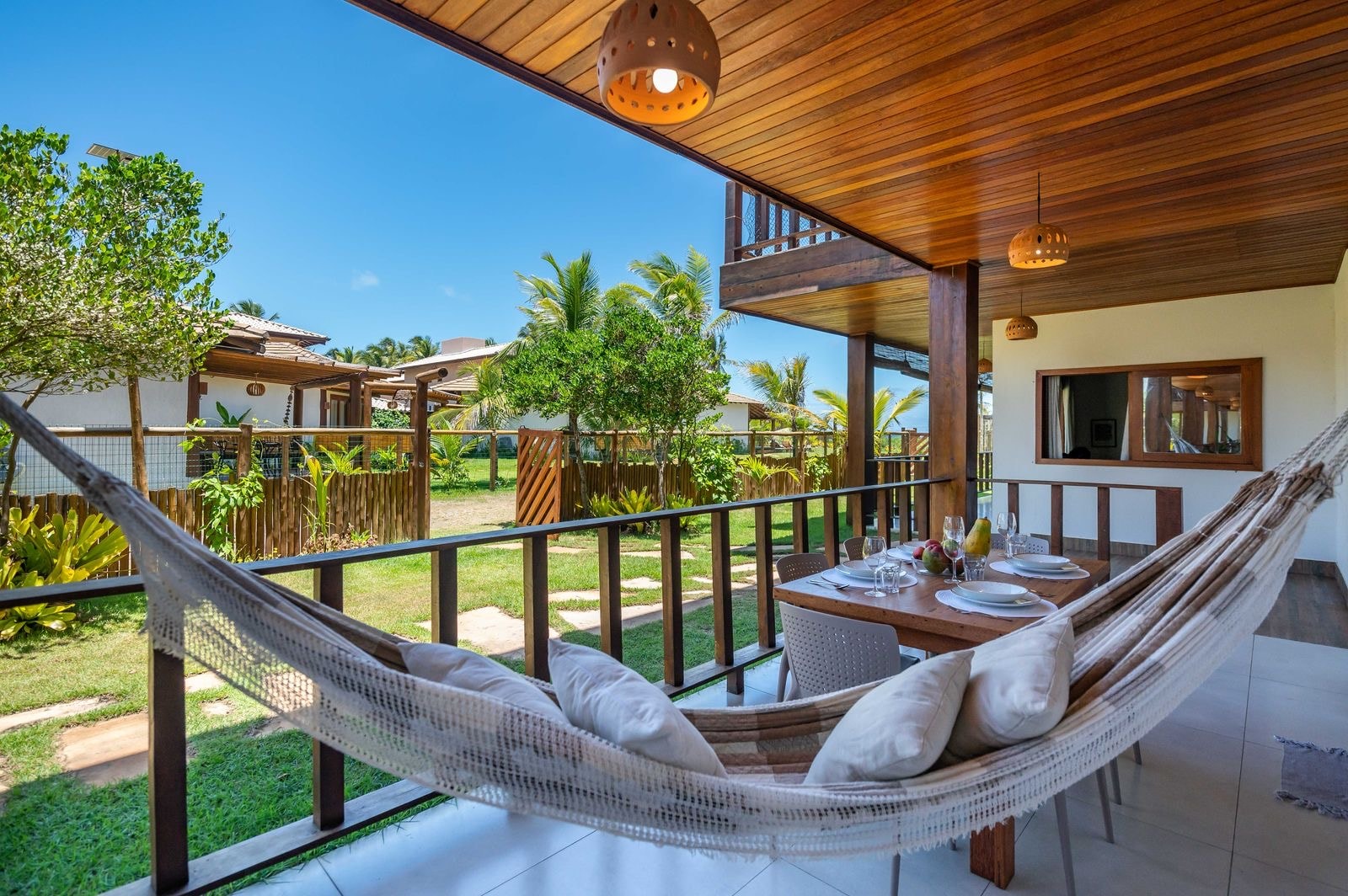 Hammock strung across a veranda beside a table set for dinner