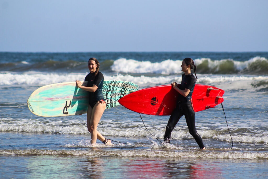 Two surfers walking out of the water at Montañita carrying their boards