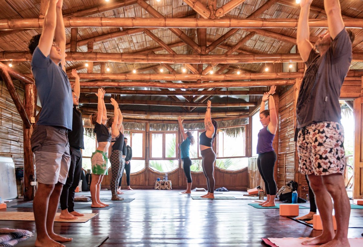 A class standing with arms raised in the bamboo shala at Casa del Sol