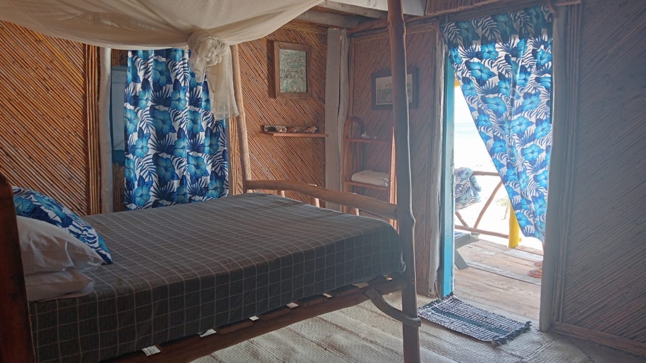 Room at Chez Andrea with mosquito net over the bed and the door open to the beach